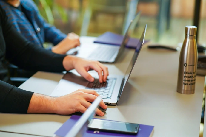 two people sitting at a table using laptops